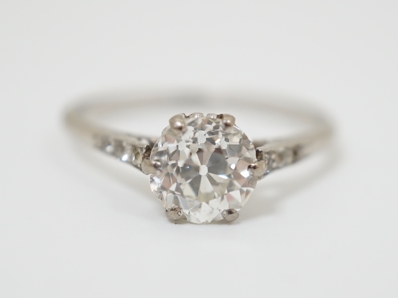 A platinum and single stone diamond ring, with diamond chip set shoulders